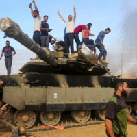 PALESTINIANS TAKE CONTROL OF AN ISRAELI TANK AFTER CROSSING THE BORDER FENCE WITH ISRAEL FROM KHAN YUNIS IN THE SOUTHERN GAZA STRIP ON OCTOBER 7, 2023. (PHOTO: STRINGER/ APA IMAGES)